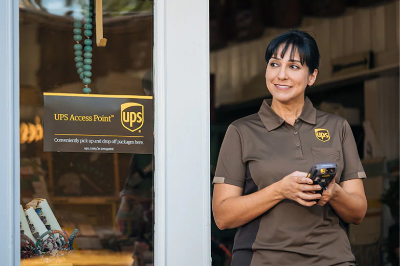 A smiling UPS employee standing by the door at an UPS access point.